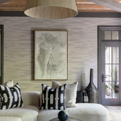 Living area design with bold art, pendant light, and chic black and white printed pillows.