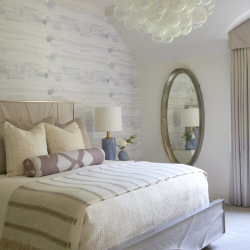 Modern chic bedroom with calming tones and a decorative wallpaper accent.